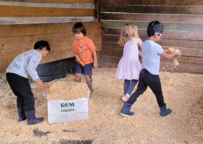 Village Learning kids putting horse stall bedding down