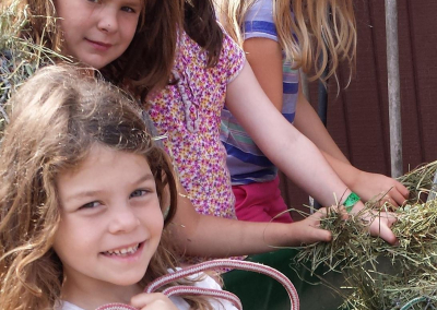 Village Learning kids holding hay nets and filling them with hay